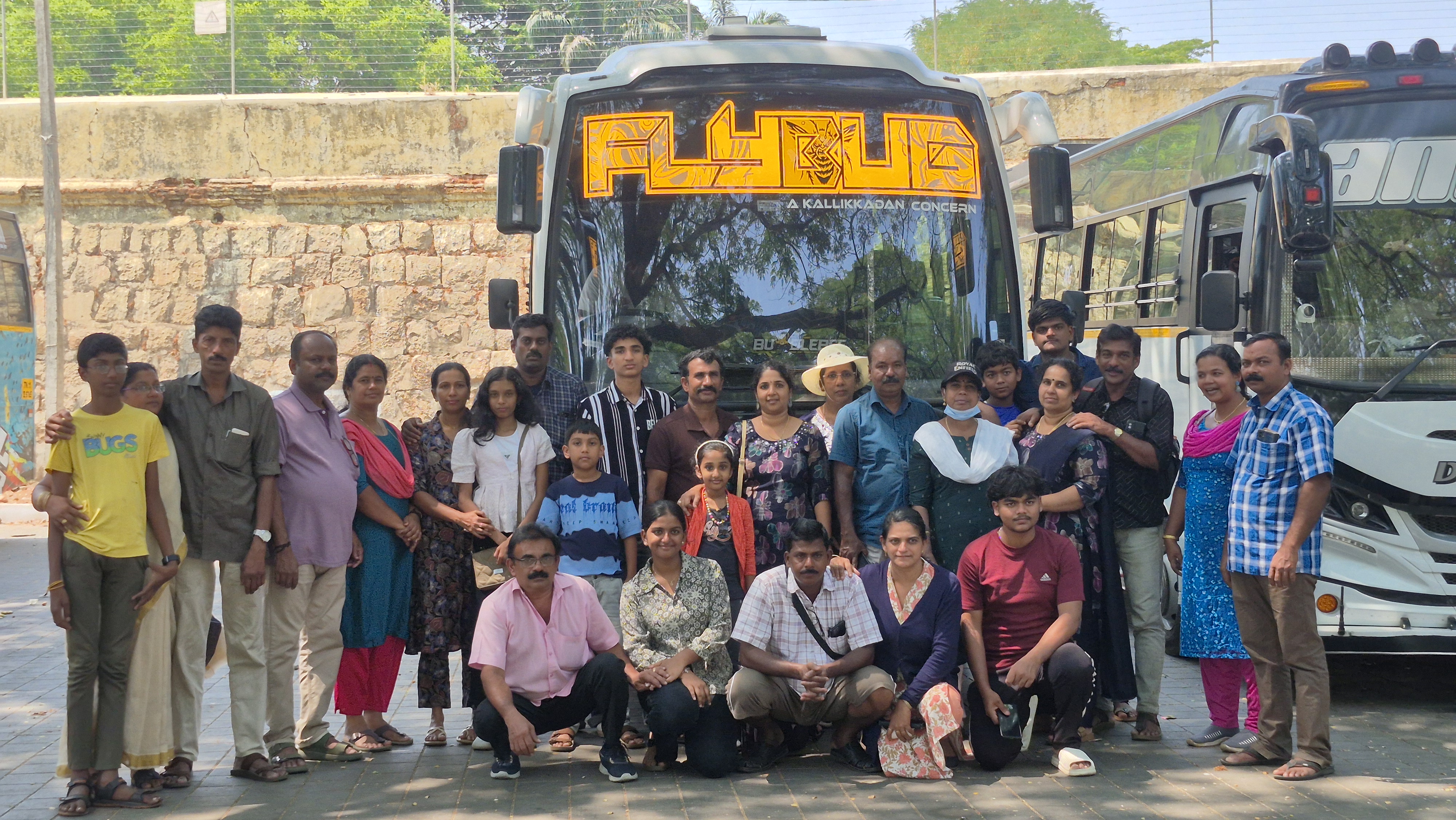 A group of travellers gathered beside a JourneyX tourist coach.